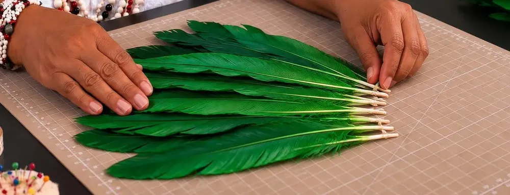 Mãos separando penas verdes sobre a base de corte